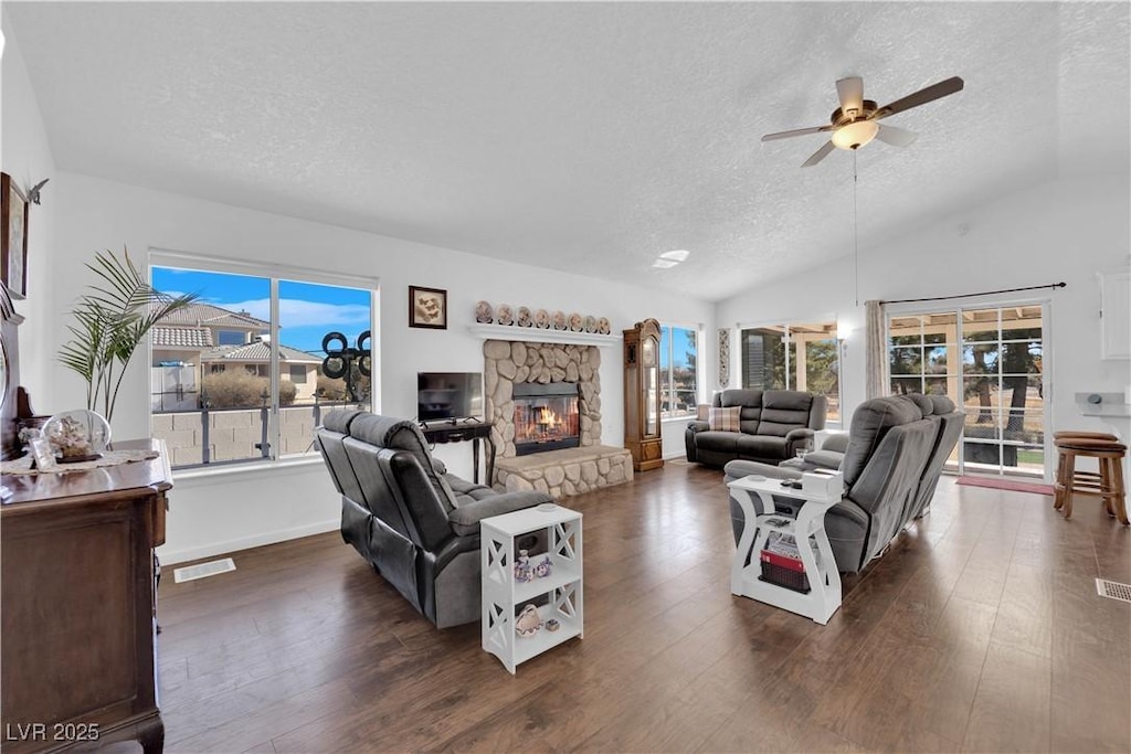 living room featuring a textured ceiling, dark wood-type flooring, vaulted ceiling, and a fireplace