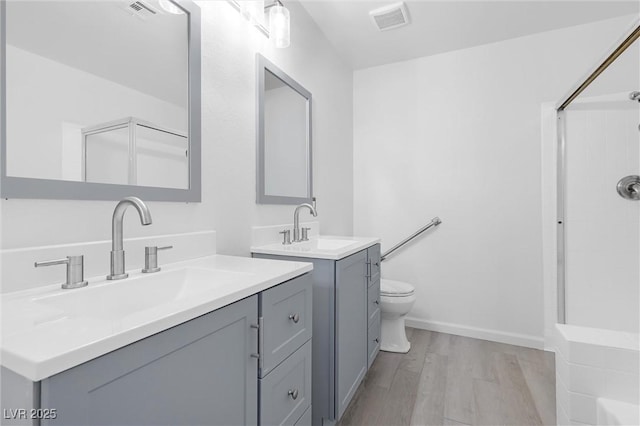 bathroom with hardwood / wood-style floors, toilet, vanity, and walk in shower