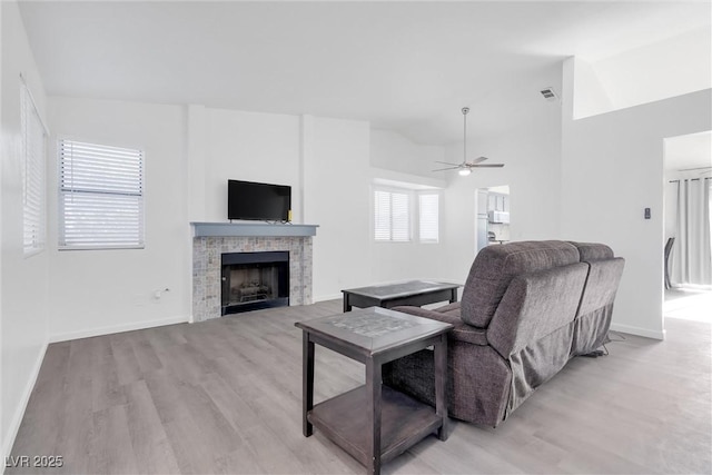 living room featuring vaulted ceiling, a wealth of natural light, light hardwood / wood-style floors, and a fireplace