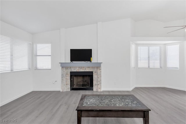 unfurnished living room featuring light hardwood / wood-style floors, a tile fireplace, and ceiling fan