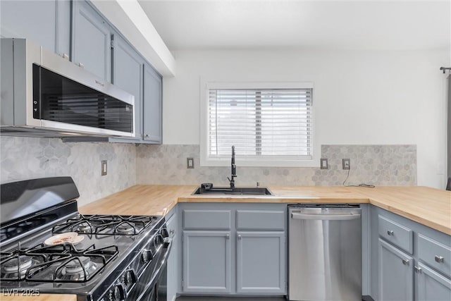 kitchen with sink, tasteful backsplash, butcher block counters, and appliances with stainless steel finishes