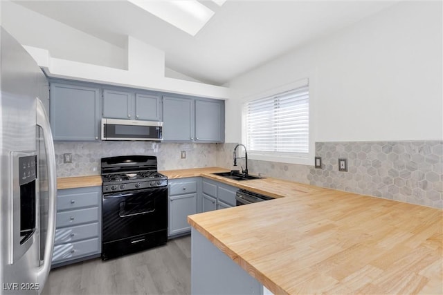 kitchen with sink, black appliances, kitchen peninsula, and wooden counters