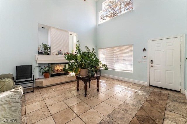 foyer with a healthy amount of sunlight, a tiled fireplace, and a towering ceiling