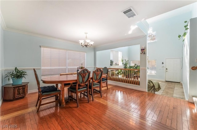 dining space featuring a notable chandelier, crown molding, and light hardwood / wood-style flooring