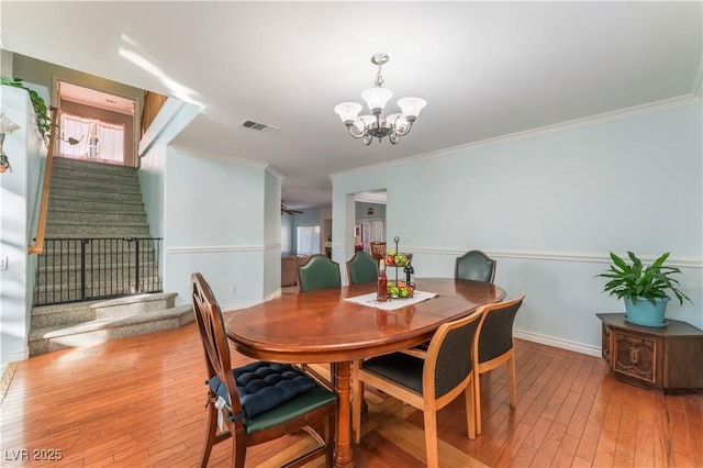 dining space featuring ornamental molding, a chandelier, and hardwood / wood-style flooring