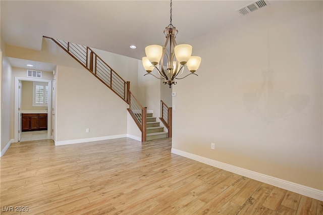 empty room featuring light wood-type flooring and an inviting chandelier