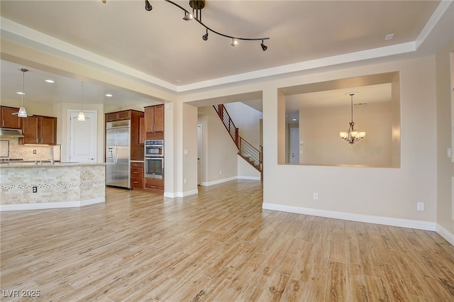 unfurnished living room with sink, light hardwood / wood-style flooring, and a chandelier