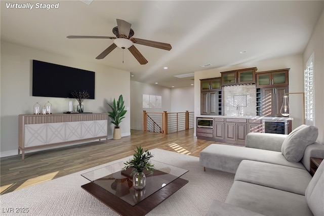 living room with ceiling fan, wet bar, and hardwood / wood-style floors