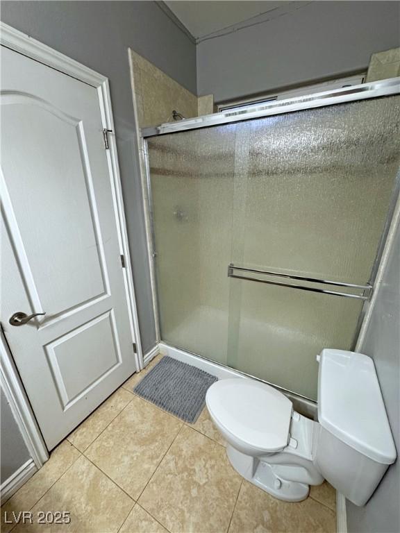 bathroom with toilet, tile patterned flooring, and a shower with shower door