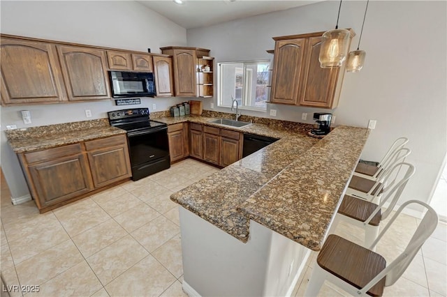 kitchen featuring black appliances, a kitchen bar, decorative light fixtures, sink, and kitchen peninsula