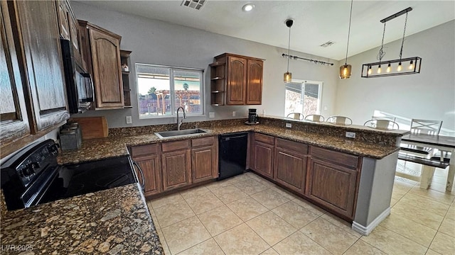 kitchen with lofted ceiling, decorative light fixtures, black appliances, kitchen peninsula, and sink