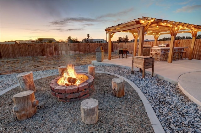 patio terrace at dusk with exterior kitchen, an outdoor fire pit, and exterior bar