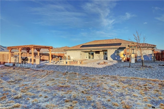 back of property with solar panels and a patio