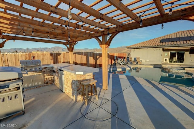 view of patio with a pergola, area for grilling, a mountain view, an outdoor bar, and a fenced in pool