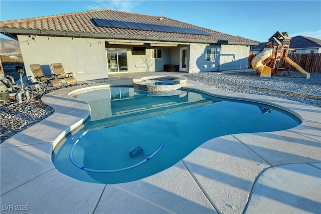 view of swimming pool featuring a playground, a patio area, and an in ground hot tub