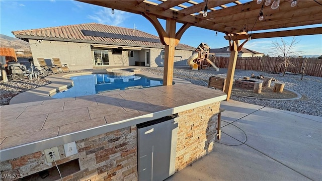 view of swimming pool with an in ground hot tub, a patio area, a playground, and a fire pit