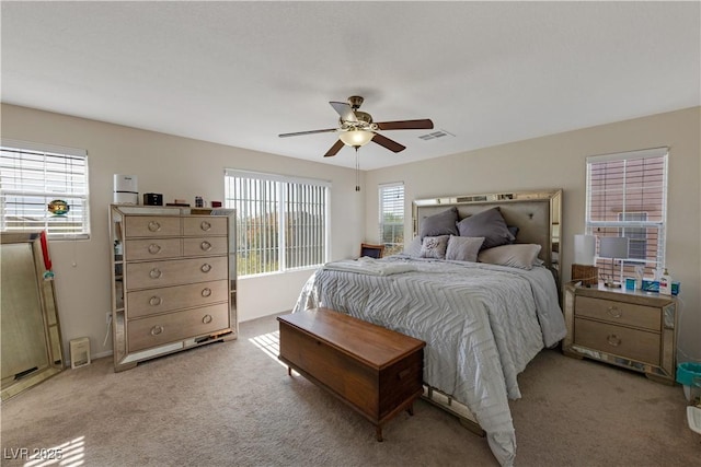 bedroom with ceiling fan, light colored carpet, and multiple windows