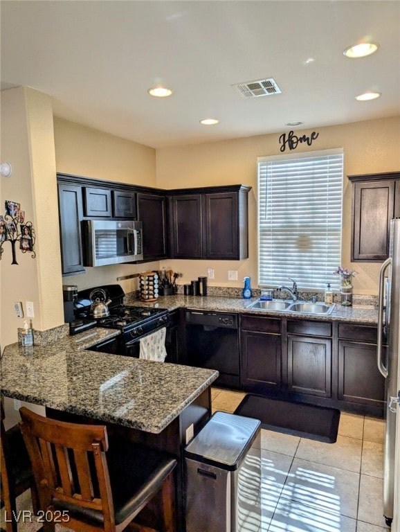 kitchen with light stone countertops, sink, kitchen peninsula, and black appliances