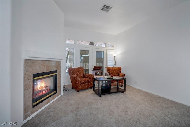 living area featuring light carpet, french doors, and a fireplace