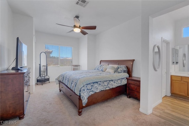 bedroom featuring ceiling fan, ensuite bath, and light carpet