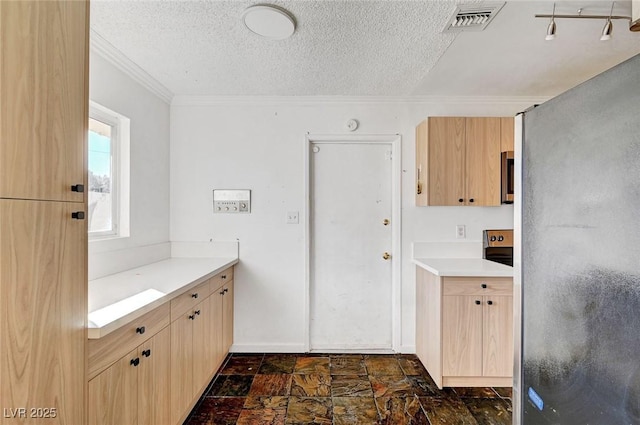 kitchen featuring light brown cabinetry, a textured ceiling, stainless steel fridge, and ornamental molding