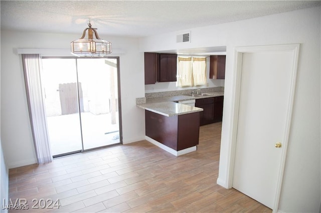 kitchen featuring sink, dark brown cabinets, pendant lighting, and a textured ceiling