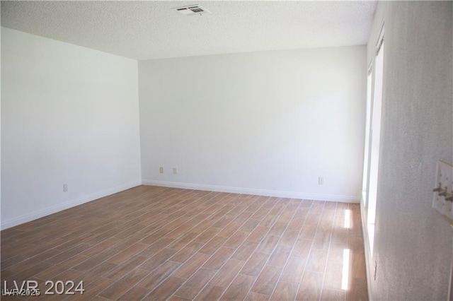 empty room with hardwood / wood-style floors and a textured ceiling