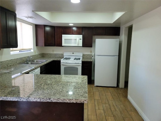 kitchen with sink, white appliances, light stone countertops, and a tray ceiling