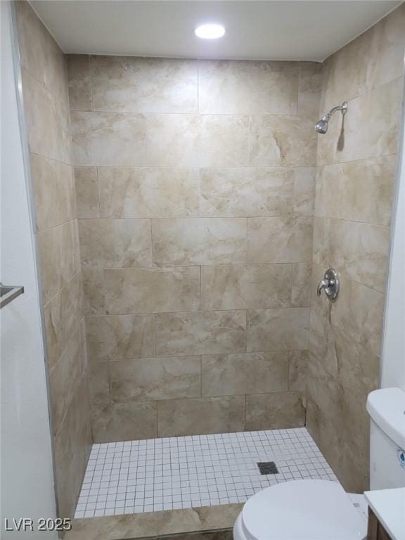 bathroom featuring vanity, toilet, and a tile shower