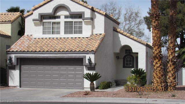 mediterranean / spanish home featuring concrete driveway, a tiled roof, and stucco siding