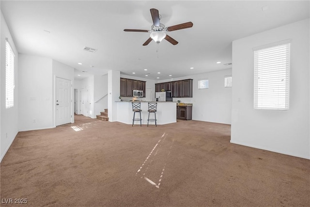 unfurnished living room featuring ceiling fan and light colored carpet