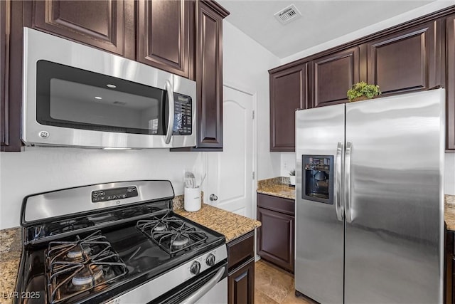 kitchen with appliances with stainless steel finishes, dark brown cabinets, and light stone countertops