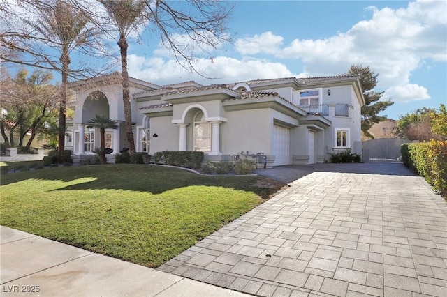 mediterranean / spanish-style home featuring a front lawn, a garage, and a balcony