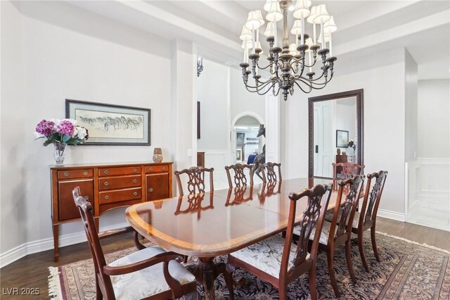 dining space featuring a chandelier, a raised ceiling, and dark hardwood / wood-style floors