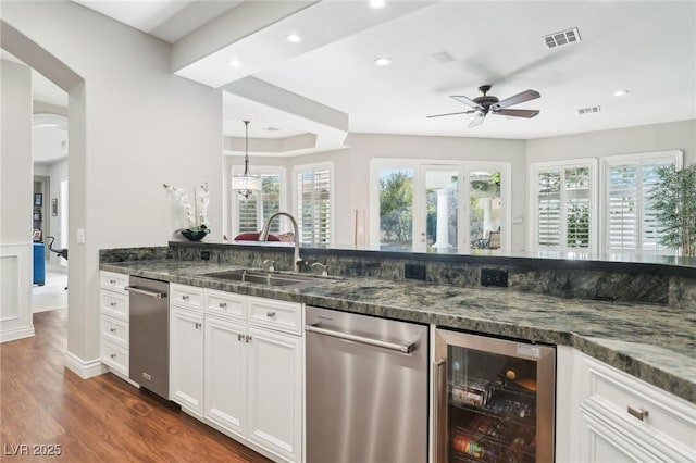 kitchen featuring dark stone countertops, wine cooler, white cabinets, and sink