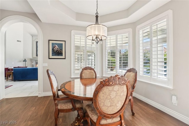 dining space with hardwood / wood-style flooring, a chandelier, and a raised ceiling