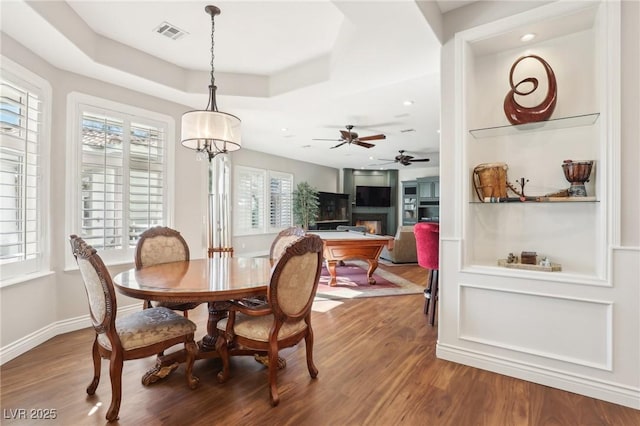 dining area featuring ceiling fan, hardwood / wood-style floors, and a raised ceiling