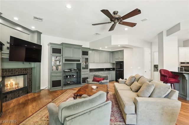 living room featuring light hardwood / wood-style floors, ceiling fan, and a fireplace