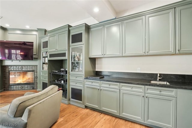 kitchen with dark stone counters, sink, and light hardwood / wood-style flooring