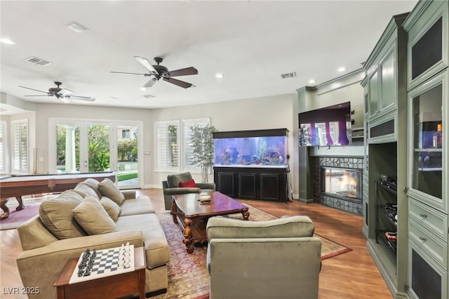 living room with ceiling fan, billiards, a fireplace, and light hardwood / wood-style floors