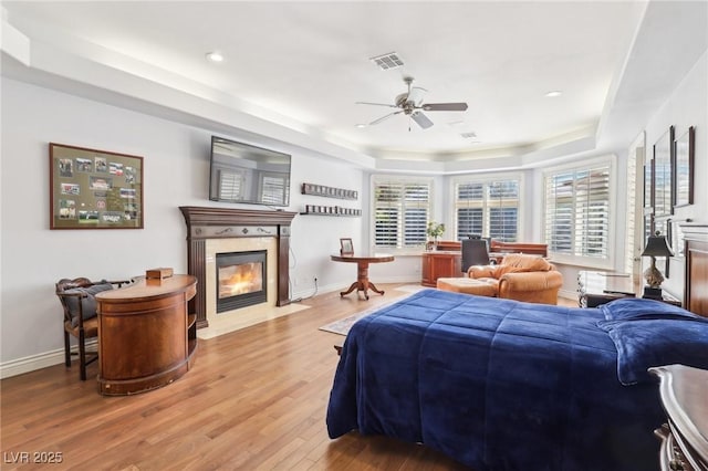 bedroom featuring ceiling fan, hardwood / wood-style flooring, and a raised ceiling