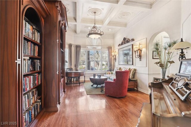 living area with beam ceiling, wood-type flooring, crown molding, and coffered ceiling