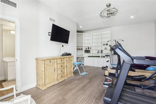 workout room featuring built in features and light hardwood / wood-style flooring