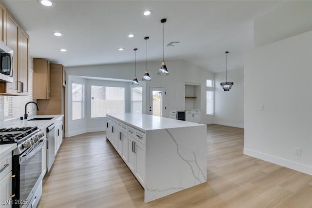 kitchen featuring pendant lighting, white cabinets, appliances with stainless steel finishes, a kitchen island, and sink