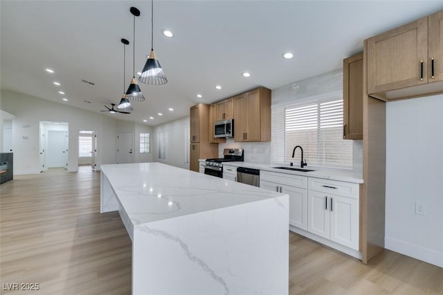 kitchen featuring a center island, sink, hanging light fixtures, appliances with stainless steel finishes, and white cabinets