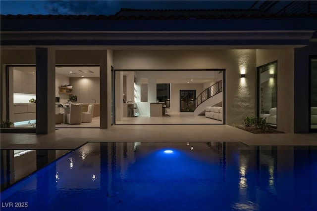 pool at night featuring a patio area