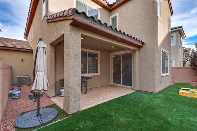 rear view of property with a lawn, central AC unit, and a patio