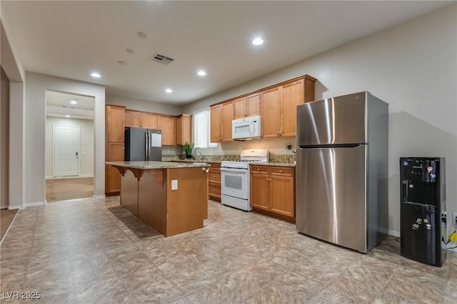 kitchen featuring a center island, a kitchen bar, sink, white appliances, and light stone counters