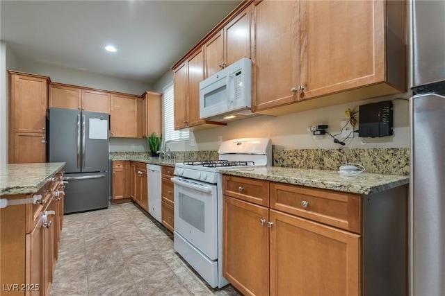 kitchen with light stone countertops, sink, and white appliances