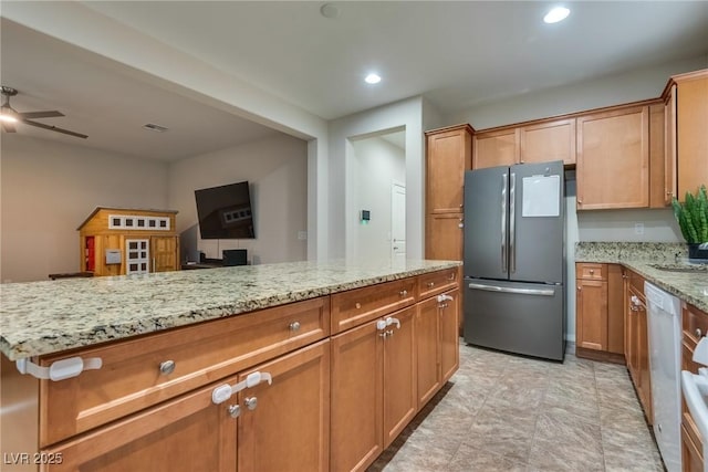 kitchen with light stone counters, stainless steel fridge, dishwasher, and ceiling fan